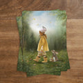 Postkarte Eiersuche von Iris Esther A6: ein kleines Mädchen mit Korb sucht im Frühlingswald Ostereier, ein Vogel sitzt auf seinem Hut
