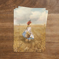Postkarte Erntemädchen von Iris Esther A6: ein Mädchen mit rotem Kopftuch und Korb geht durch ein goldenes Weizenfeld