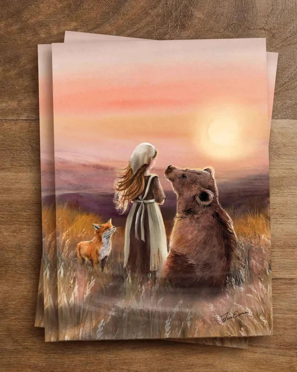Postkarte Freunde in der Abendsonne von Iris Esther A6: eine junge Frau steht im goldenen Abendlicht im Gras, neben ihr ein Fuchs und ein Bär