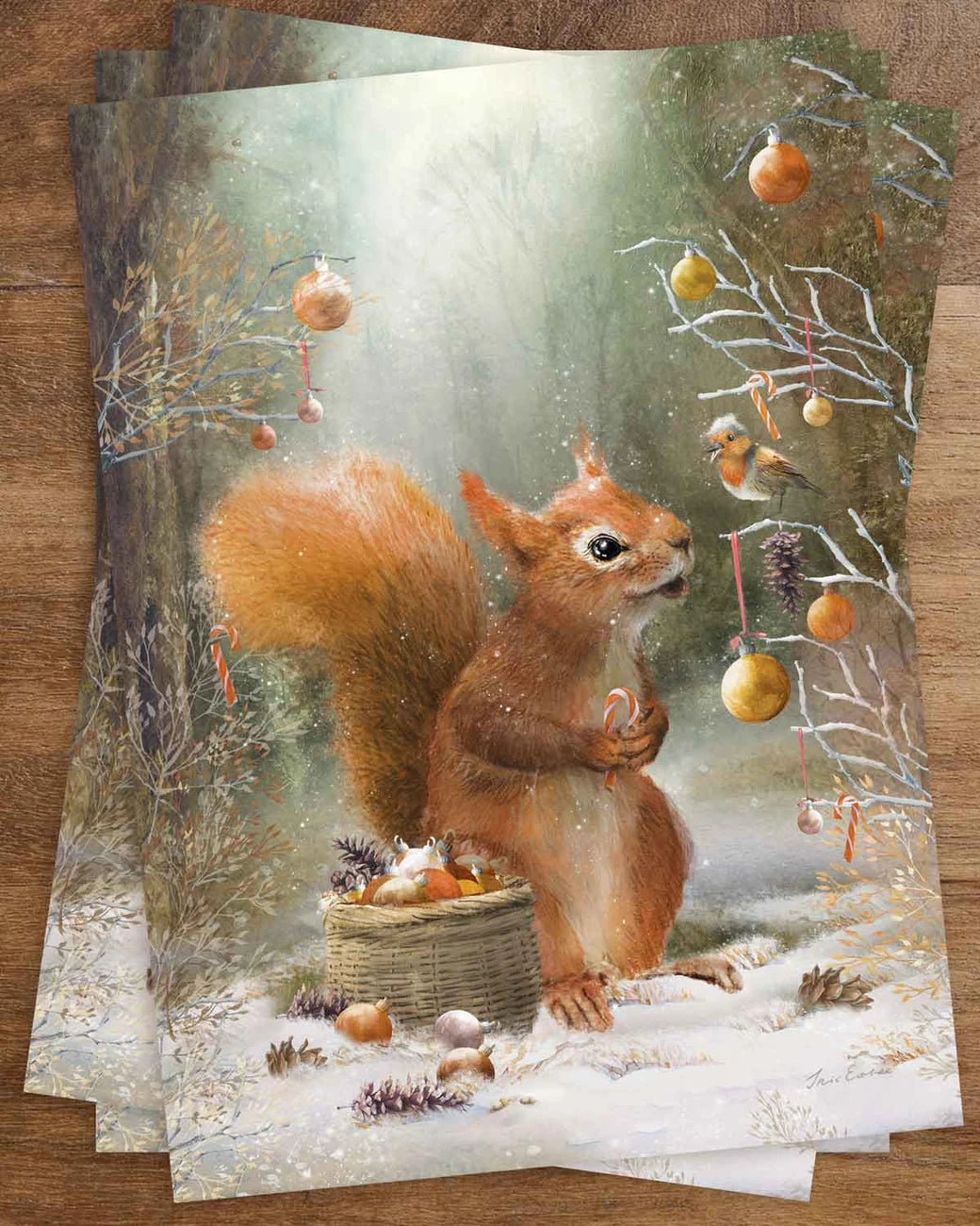 Postkarte Kleiner Helfer von Iris Esther A6: ein Eichhörnchen mit Korb voller Christbaumkugeln und einer Zuckerstange schmückt im Winterwald einen Baum