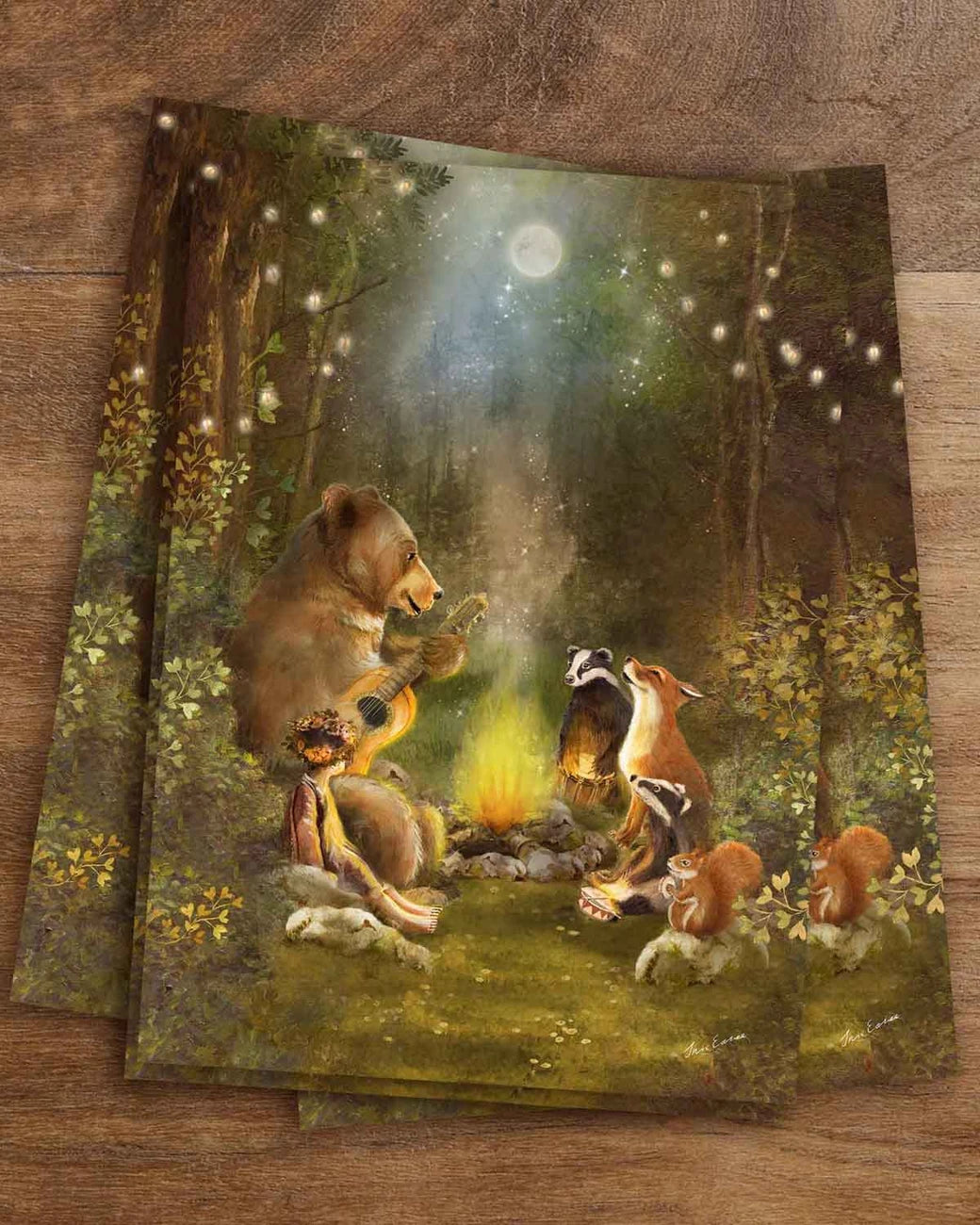 Postkarte Lagerfeuer von Iris Esther A6: ein Bär spielt Gitarre am Lagerfeuer, Fuchs, Dachse, Eichhörnchen und ein Kind mit Blumenkranz hören zu