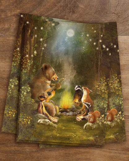 Postkarte Lagerfeuer von Iris Esther A6: ein Bär spielt Gitarre am Lagerfeuer, Fuchs, Dachse, Eichhörnchen und ein Kind mit Blumenkranz hören zu