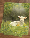 Postkarte Lamm mit Küken von Iris Esther A6: ein wolliges Lamm und ein gelbes Küken ruhen nebeneinander zwischen Gänseblümchen
