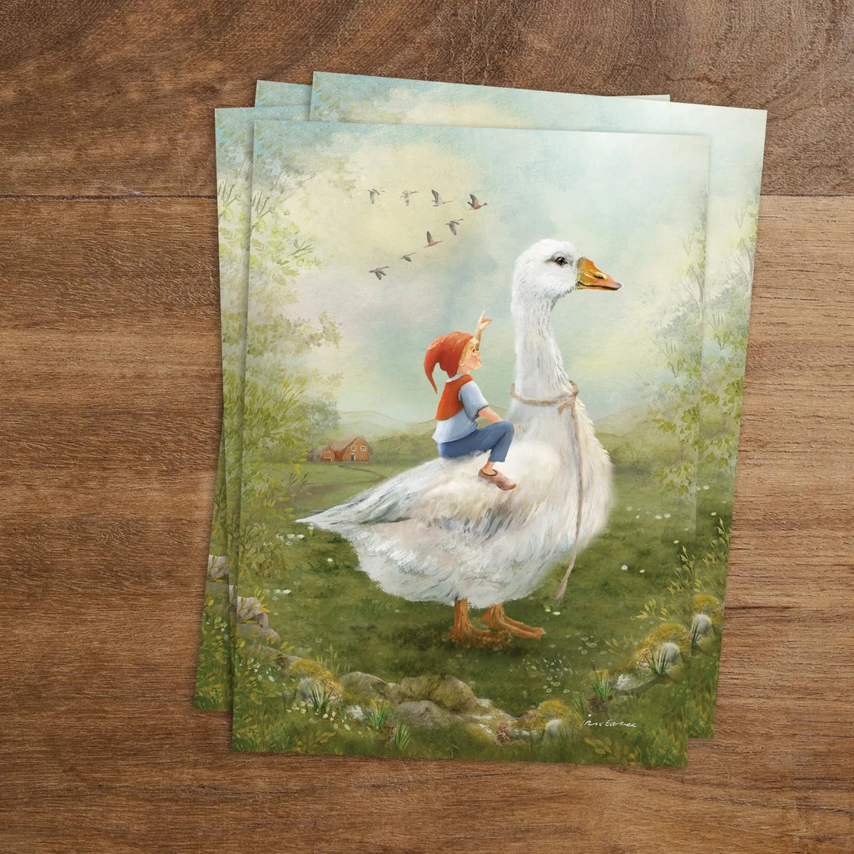 Postkarte Nils Holgersson auf der Wiese von Iris Esther A6: ein kleiner Junge sitzt auf dem Rücken einer großen weißen Gans auf einer Wiese