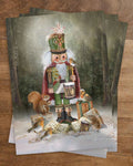 Postkarte Nussknacker von Iris Esther A6: der Nussknacker mit Trommel steht auf einer verschneiten Lichtung, Rotkehlchen, eine Maus und ein Eichhörnchen schauen zu