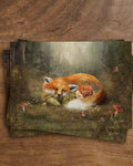 Postkarte Waldwiegenlied von Iris Esther A6: ein Kind und ein Fuchs haben sich zwischen Farn und Herbstlaub zum Schlafen aneinandergekuschelt