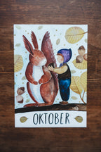 Monatskarte Oktober aus dem Set von Joringl, Wichtel mit Eichhörnchen zwischen gelben Blättern, auf Holz fotografiert