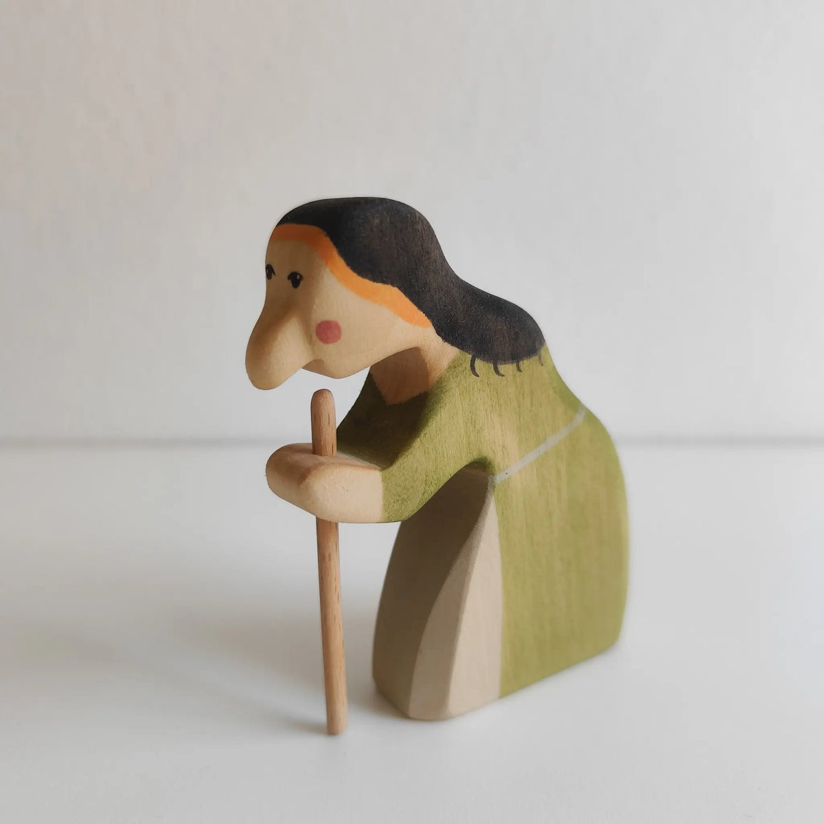 Juharka Holzfigur Hexe aus Ahornholz, gebeugte Märchenhexe im grünen Kleid mit dunklem Haar und Holzstock