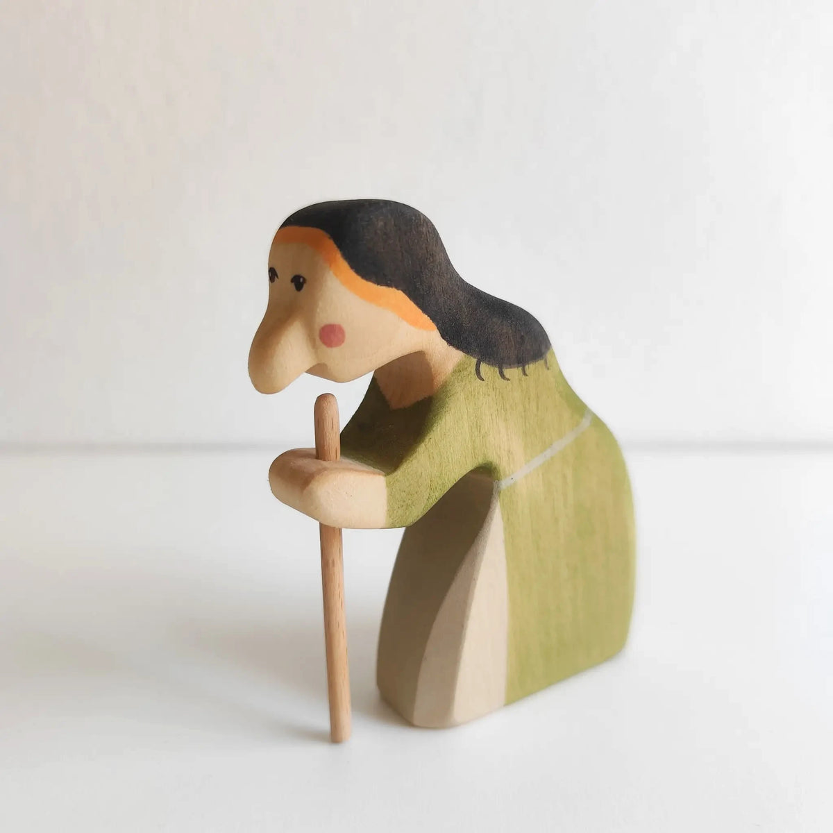 Juharka Holzfigur Hexe aus Ahornholz, gebeugte Märchenhexe im grünen Kleid mit dunklem Haar und Holzstock