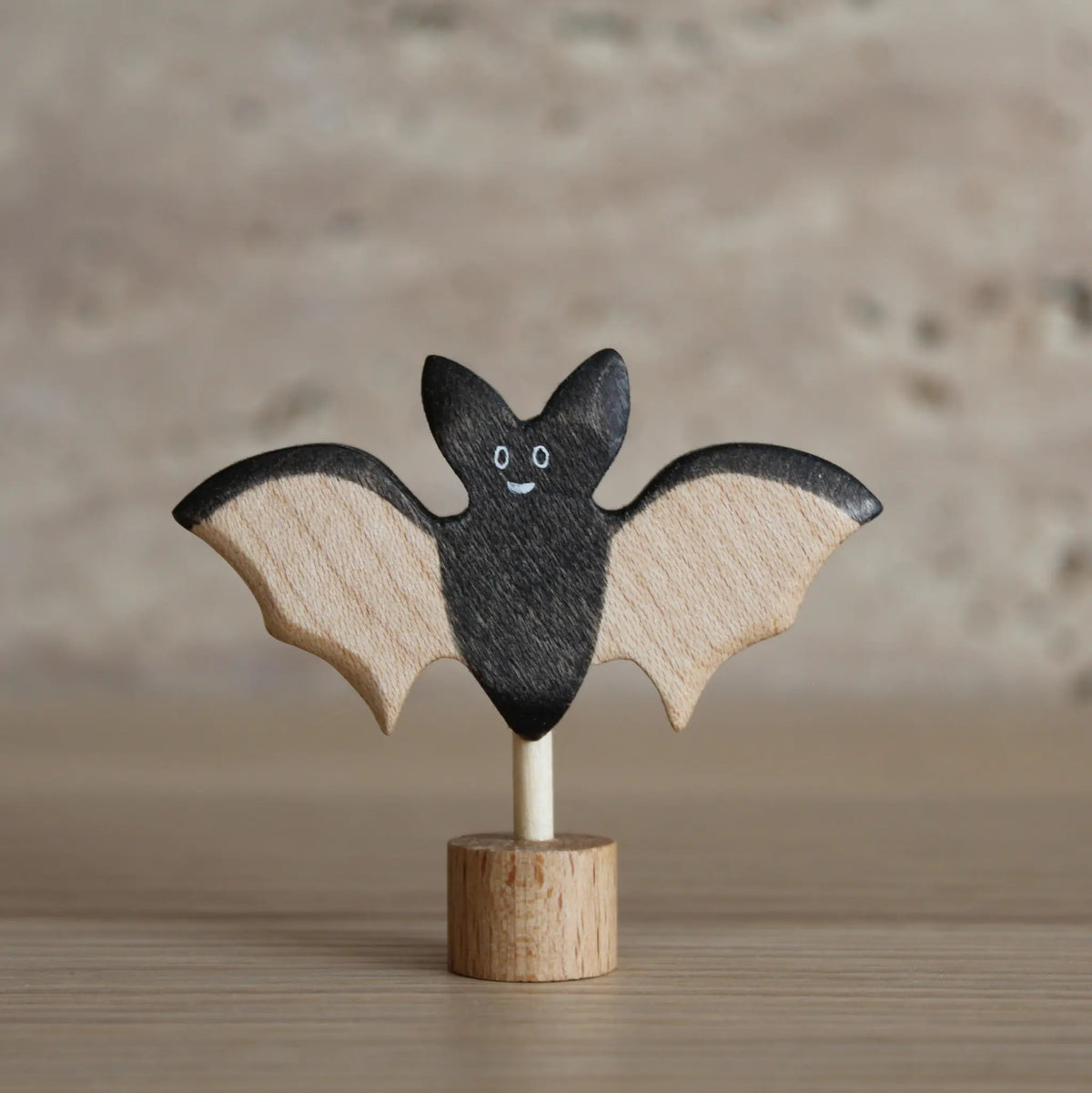 Juharka Stecker Fledermaus aus Ahornholz, lächelnde schwarze Fledermaus mit hellen Holzflügeln auf Holzfuß