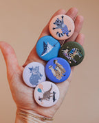 Hand mit sechs Buttons der starken Bande von Liesels Wicht, oben der Waschbär