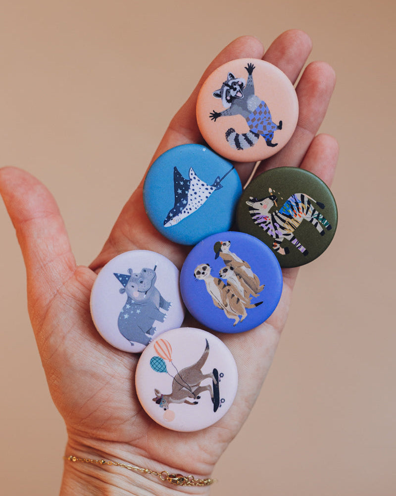 Hand mit sechs Buttons der starken Bande von Liesels Wicht, oben der Waschbär