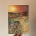 Kunstdruck Blumenwiese von Lot Bouwes A4, Sommerwiese mit Mohn und Sonnenblumen vor einem roten Haus, Foto in der Hand