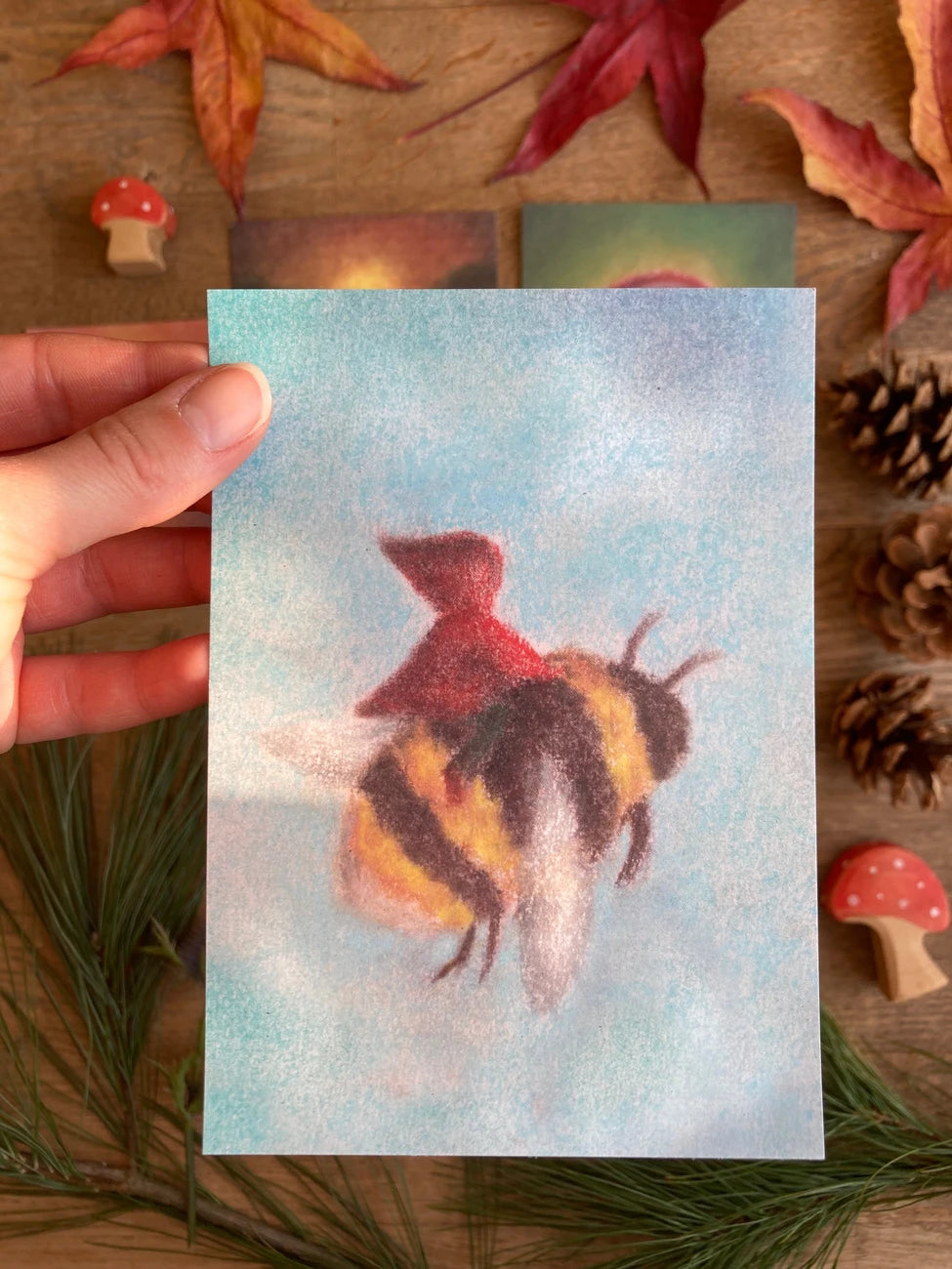 Postkarte Biene von Lot Bouwes A6 in der Hand gehalten über Herbstlaub, Foto