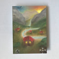 Postkarte Dorf von Lot Bouwes A6: kleines Dorf mit roten Häusern in einem Bergtal, ein Fluss schlängelt sich durch, Wasserfall, Abendhimmel, weiße Blumen vorne