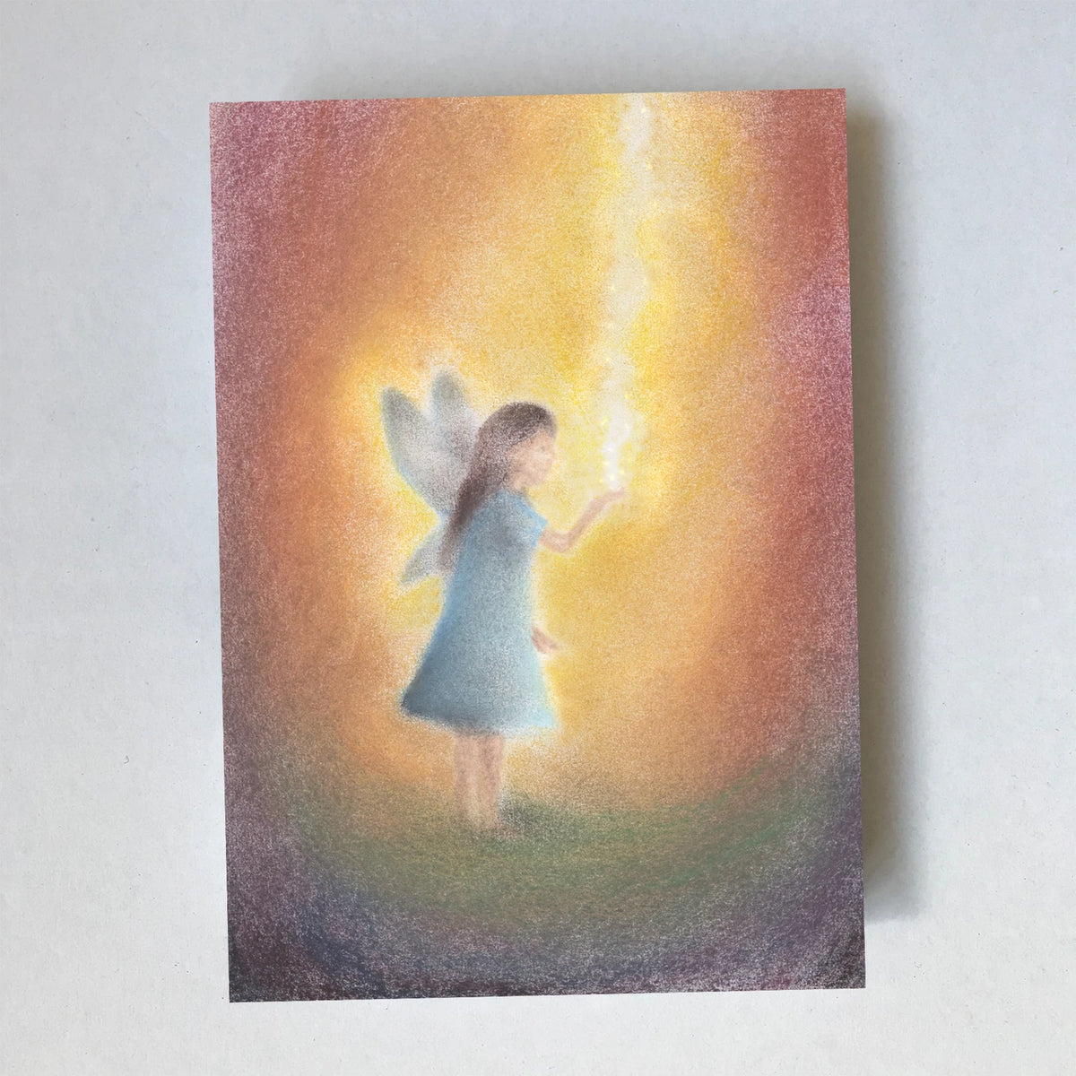 Postkarte Feenstaub von Lot Bouwes A6: eine kleine Fee in blauem Kleid mit Flügeln streut glitzernden Feenstaub, goldenes Licht