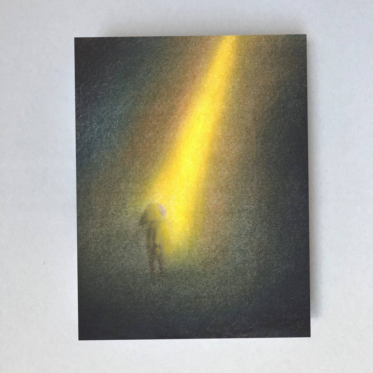 Postkarte Lichtstrahl von Lot Bouwes A6: eine kleine Gestalt steht in einem goldenen Lichtstrahl, der durch die Dunkelheit fällt