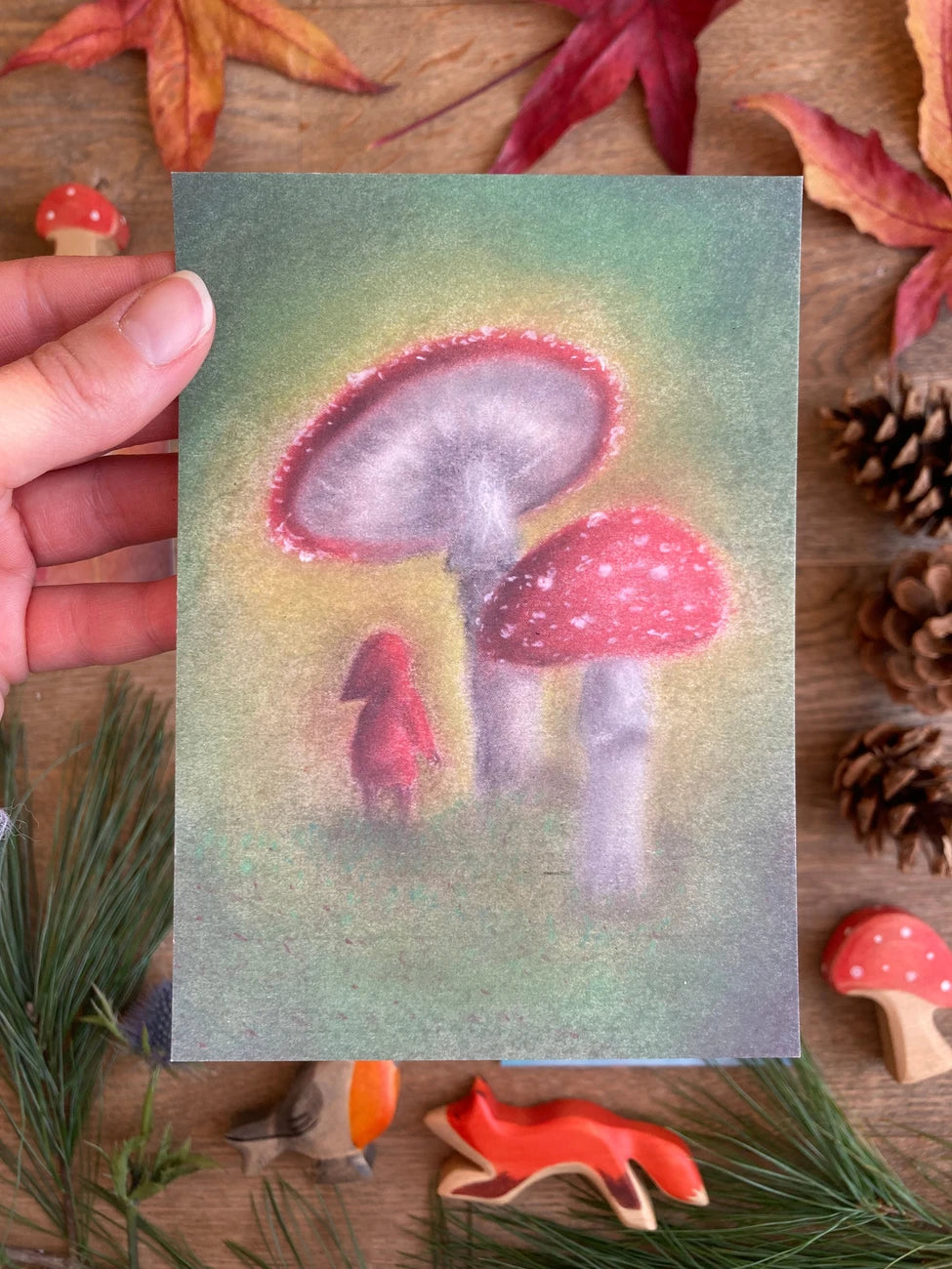 Postkarte Pilz von Lot Bouwes A6 in der Hand gehalten über Herbstlaub, Foto