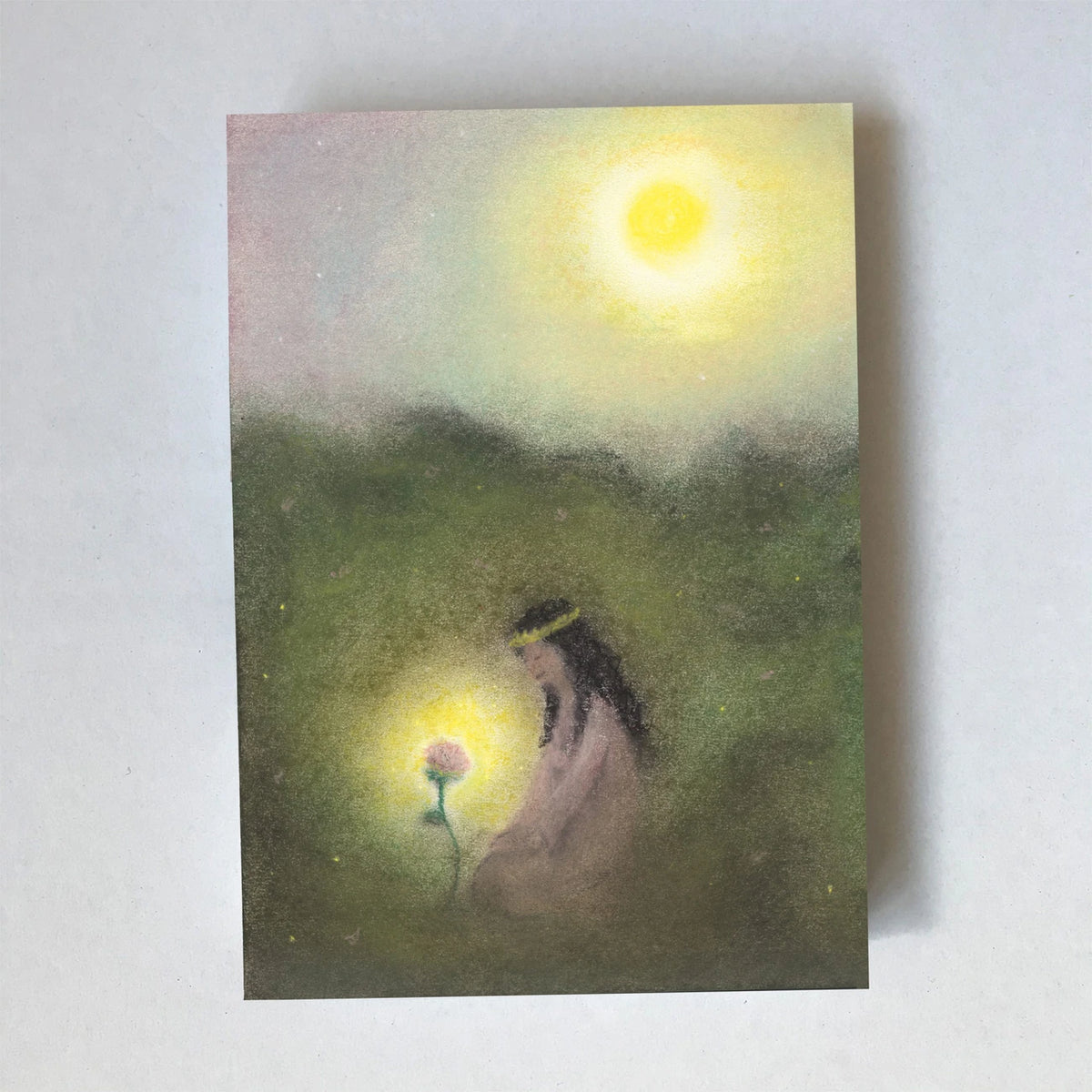 Postkarte Rose von Lot Bouwes A6: eine Prinzessin mit langem Haar kniet im hohen Gras bei einer leuchtenden Rose, Sonne am gelben Himmel