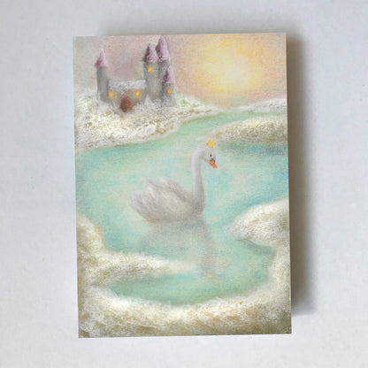 Postkarte Schwanenmeer von Lot Bouwes A6: ein weißer Schwan gleitet über einen türkisen See, im Hintergrund ein Schloss in den Wolken, goldene Sonne