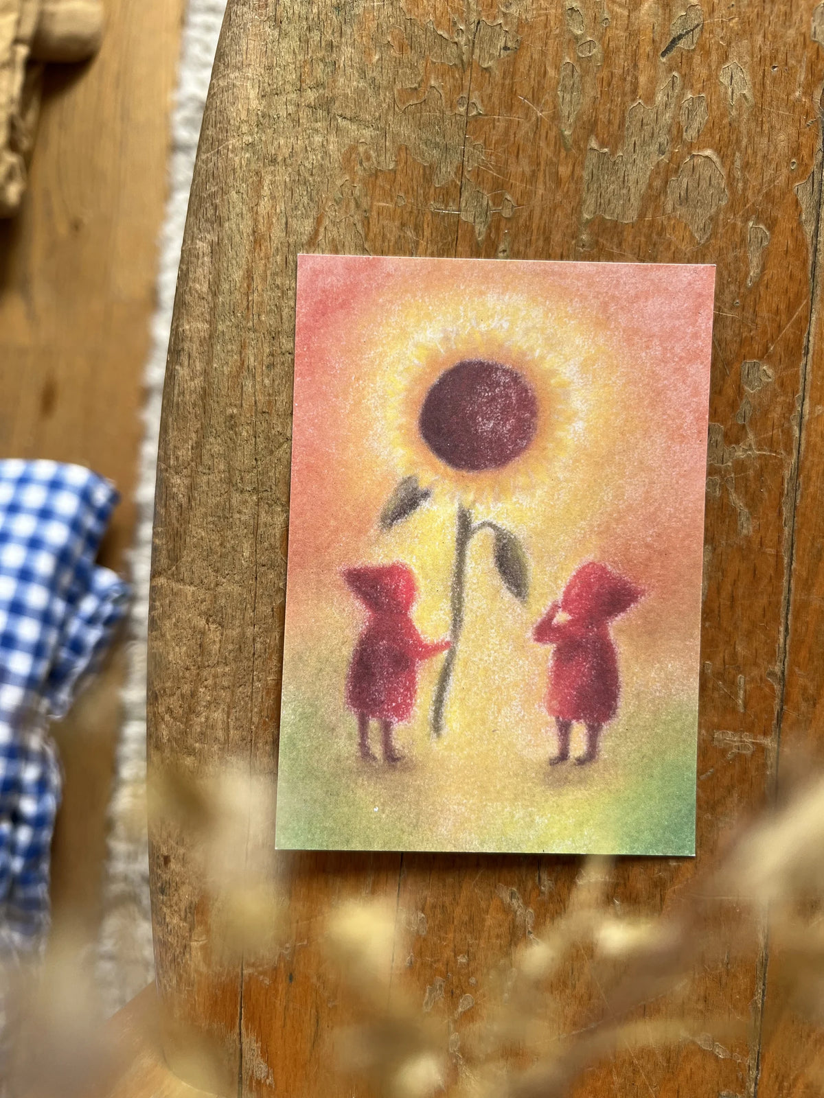 Postkarte Sonnenblume von Lot Bouwes A7 in Nahaufnahme, zwei rote Wichtel unter einer großen Sonnenblume
