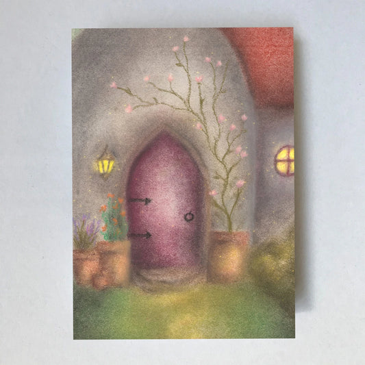 Postkarte Tür von Lot Bouwes A6: eine runde lila Holztür in einem Wichtelhaus mit Laterne, Blumentöpfen, rankendem Blütenzweig und einem leuchtenden Fenster