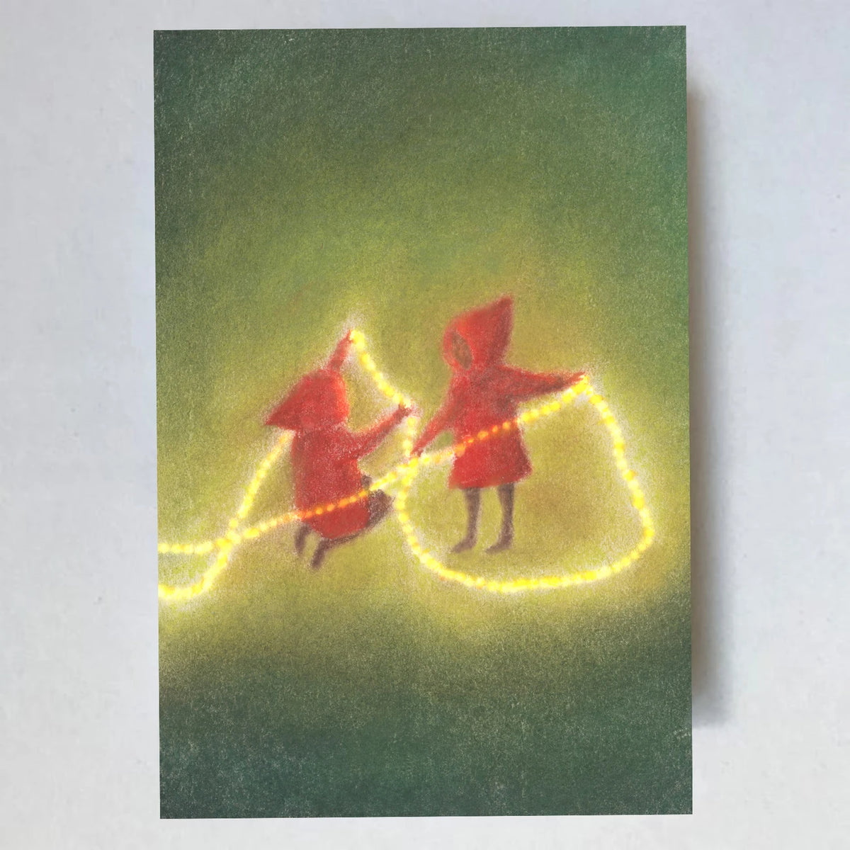Postkarte Weihnachtslichter von Lot Bouwes A7: zwei Wichtel tragen eine leuchtende Lichterkette durchs Grüne
