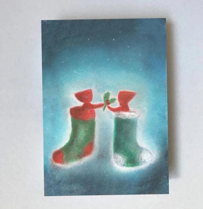 Postkarte Weihnachtssocken von Lot Bouwes A7: zwei Wichtel schauen aus zwei Weihnachtssocken in Rot und Grün