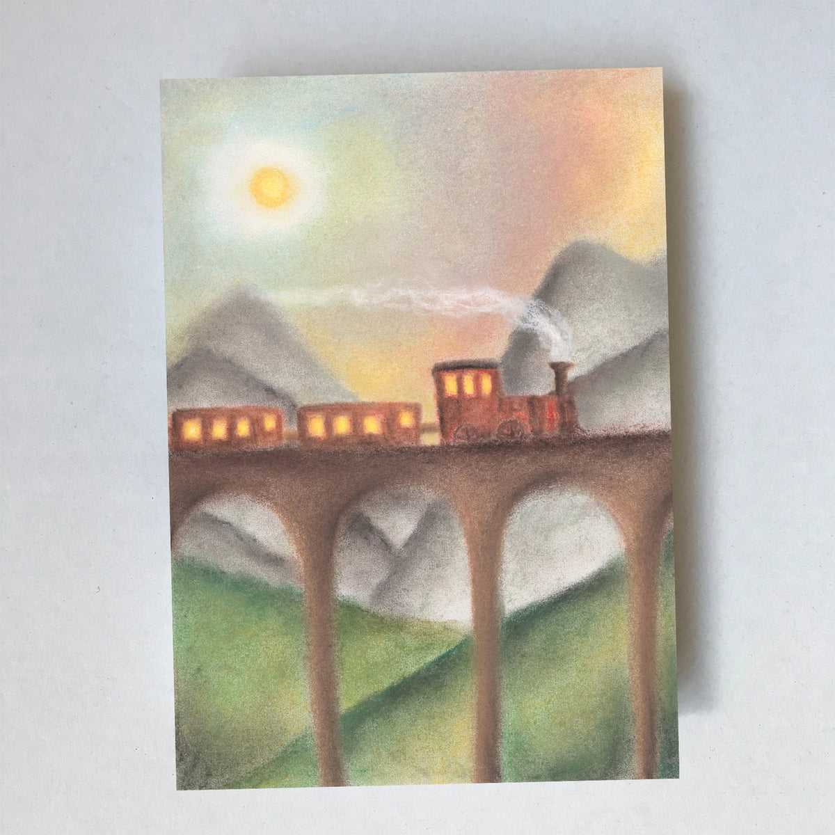 Postkarte Zug von Lot Bouwes A6: eine kleine rote Eisenbahn fährt über ein hohes Steinviadukt, Berge im Hintergrund, Sonne