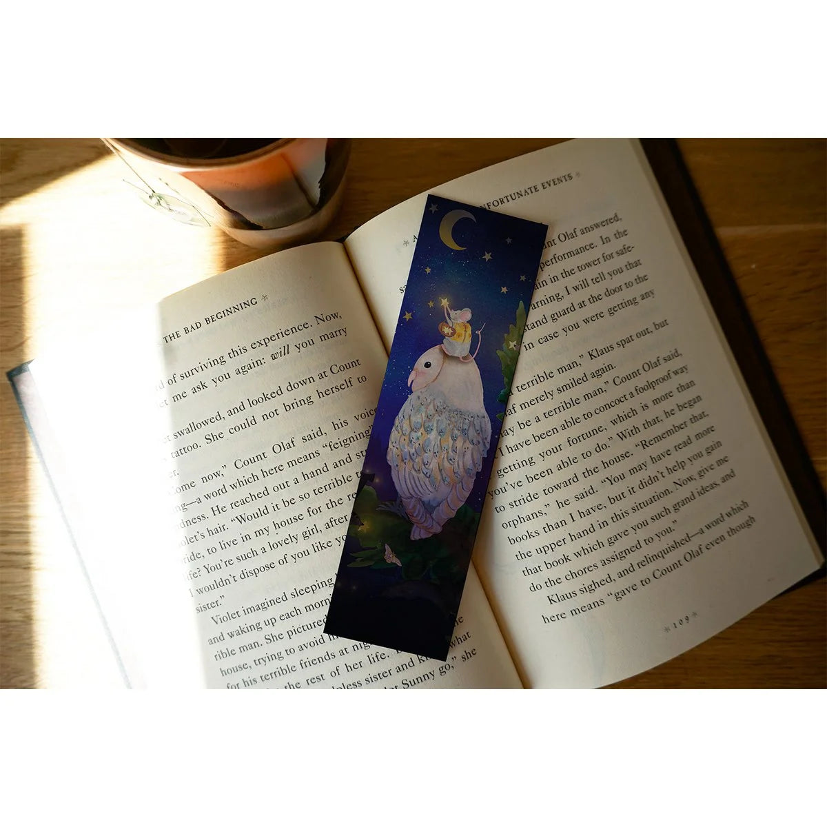 Lotte Drouen Lesezeichen Mäuschen, das Sterne aufhängt, Maus auf dem Kopf einer Eule hängt unter der Mondsichel goldene Sterne auf, auf einem aufgeschlagenen Buch