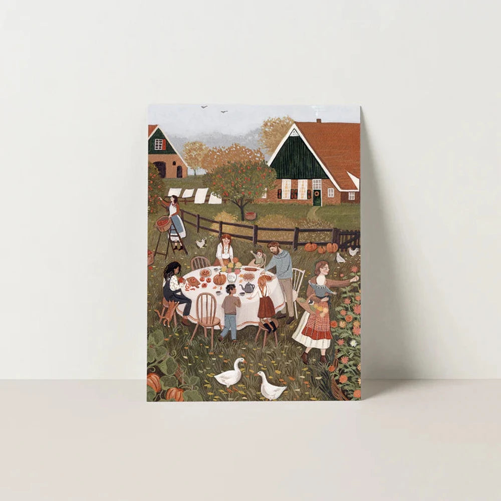 Postkarte Erntesaison von Robin Pieterse A6: eine Familie feiert an einer langen Tafel im Garten das Erntefest, Körbe voller Äpfel und Kürbisse, Gänse laufen umher