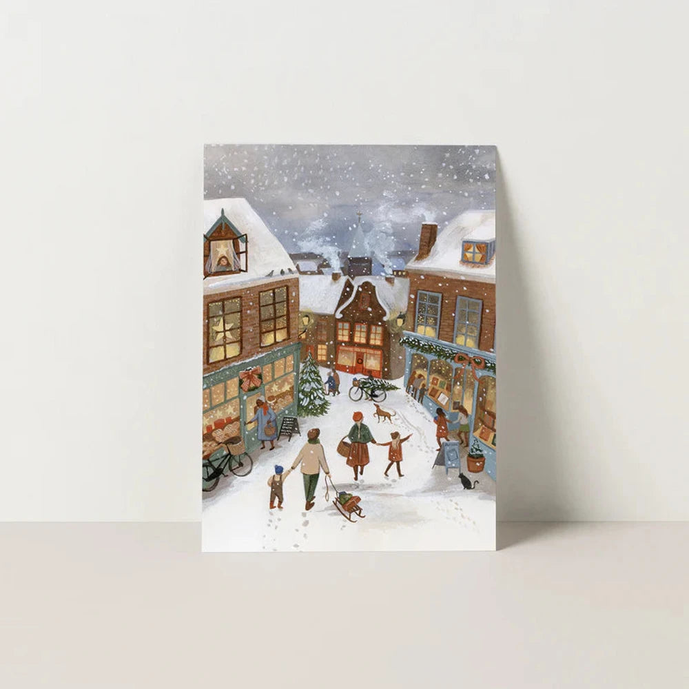 Postkarte Feierliche Gasse von Robin Pieterse A6: eine verschneite Dorfgasse mit warm erleuchteten Häuschen am Abend