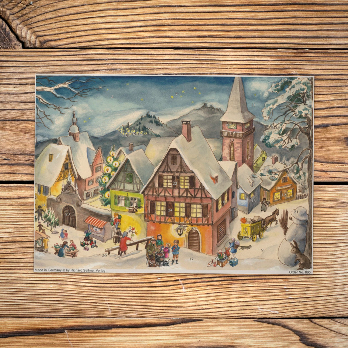 Sellmer Adventskalender Verschneites Dorf A4 auf einem Holztisch