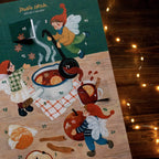 Adventskalender Wichtel von Studio Satsch A4 auf einem Holztisch mit Lichterkette