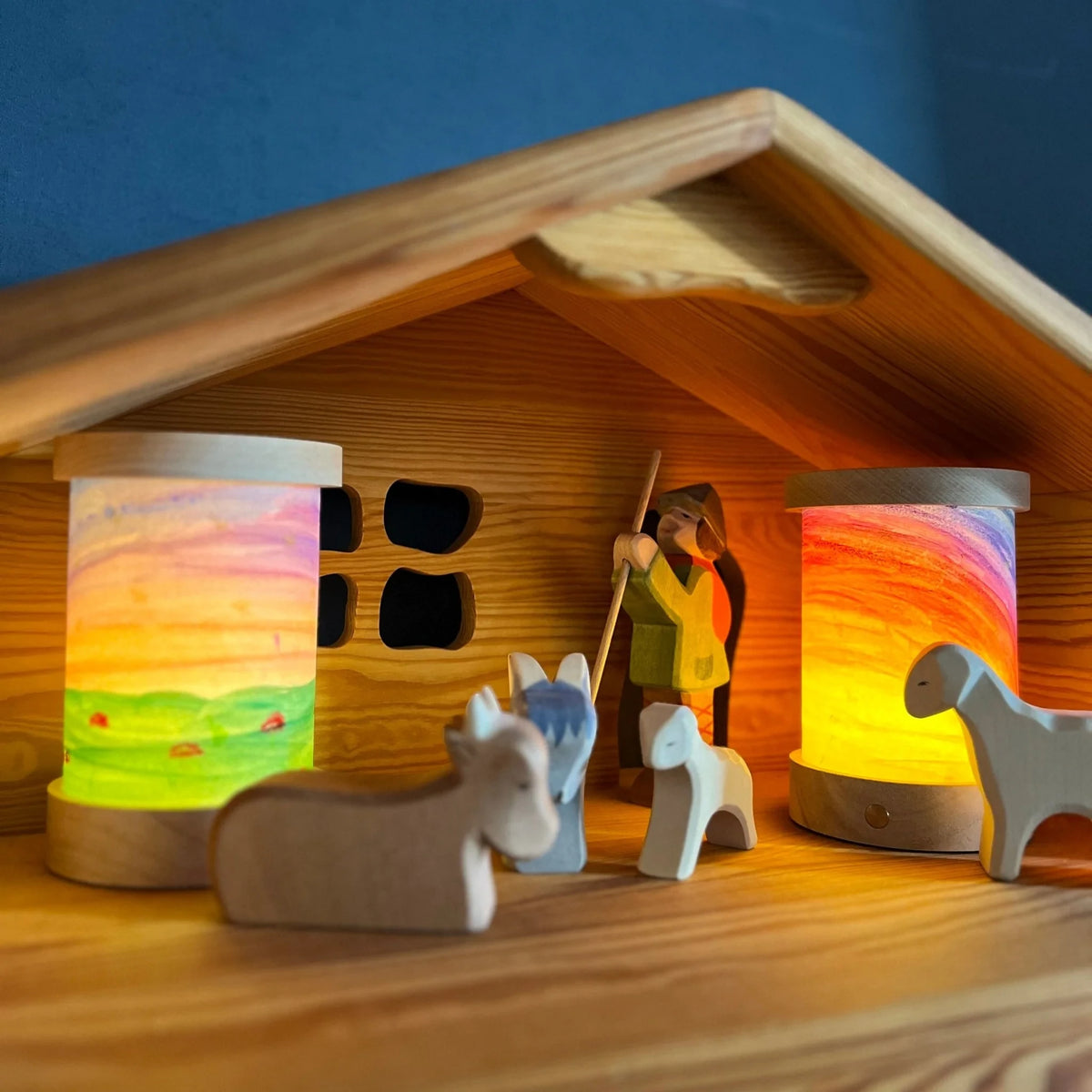 Toverlux Lichtkartenpapier zum Selbstgestalten: zwei leuchtende Laternen mit bemalten Lichtkarten in einem Holzstall mit Figuren