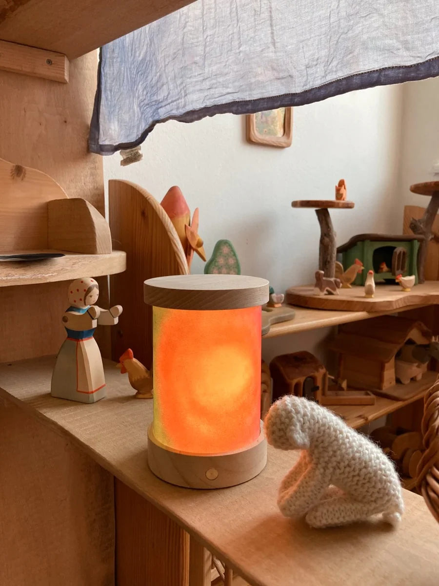 Toverlux Lichtkartenpapier zum Selbstgestalten: selbst bemalte Lichtkarte leuchtet in der Laterne im Kinderzimmerregal neben einem Holzschaf