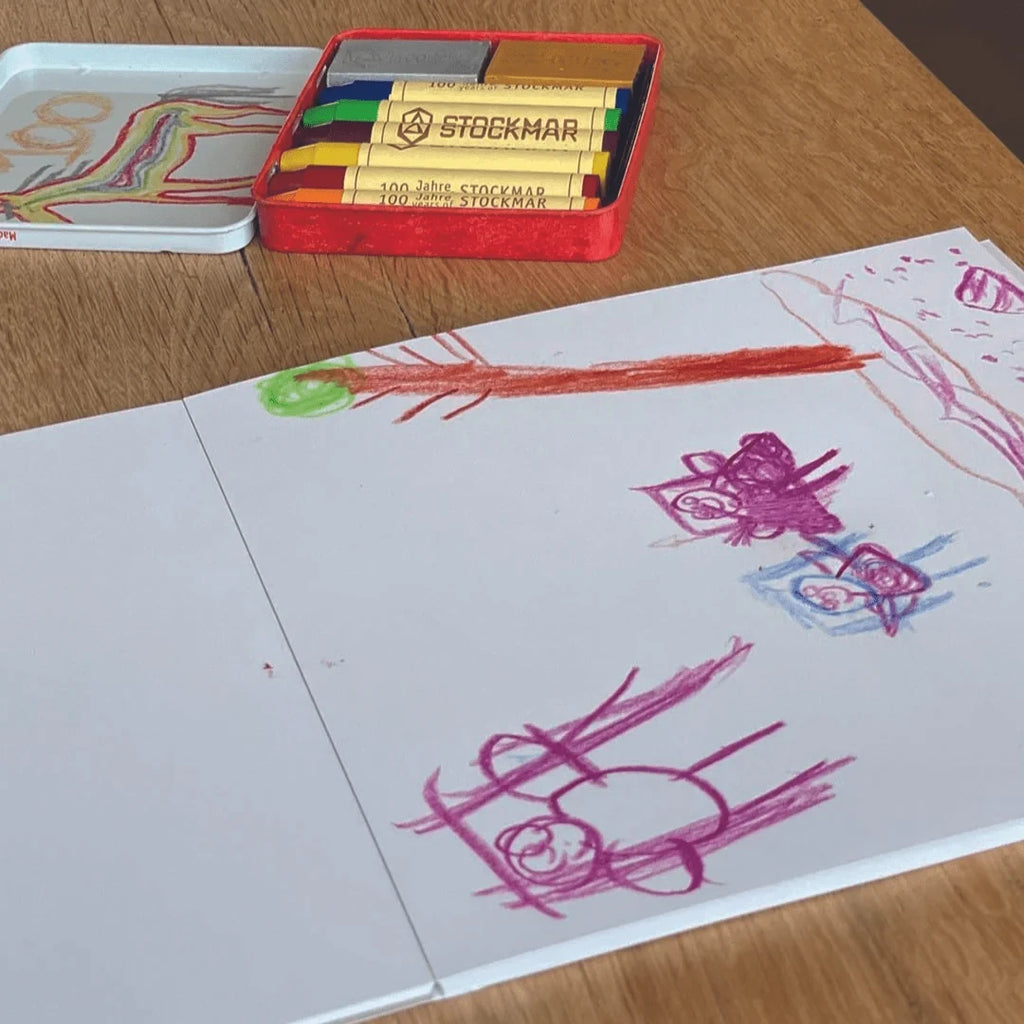 Toverlux DIY Set Stockmar Wachsmalstifte mit Motivpapier: fertig bemaltes Motivpapier neben der Stiftedose