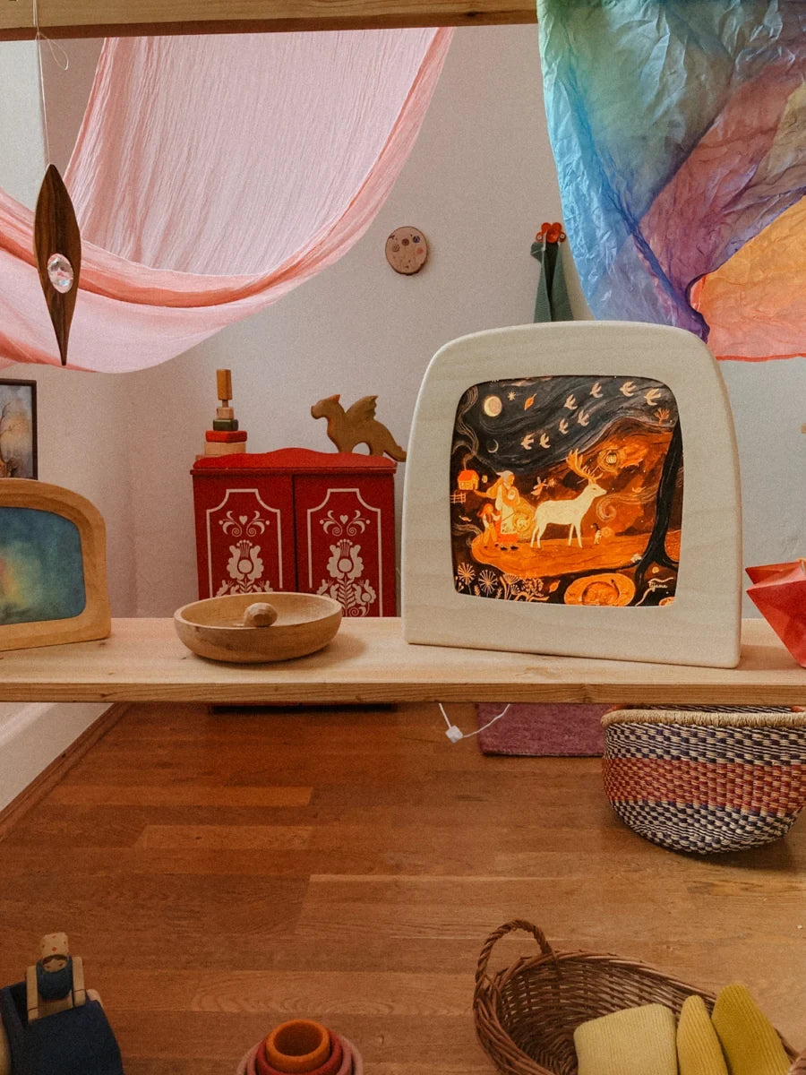 Magische Lampe Toverlux mit leuchtendem Hirschmotiv auf einem Regal im Kinderzimmer unter Seidentüchern