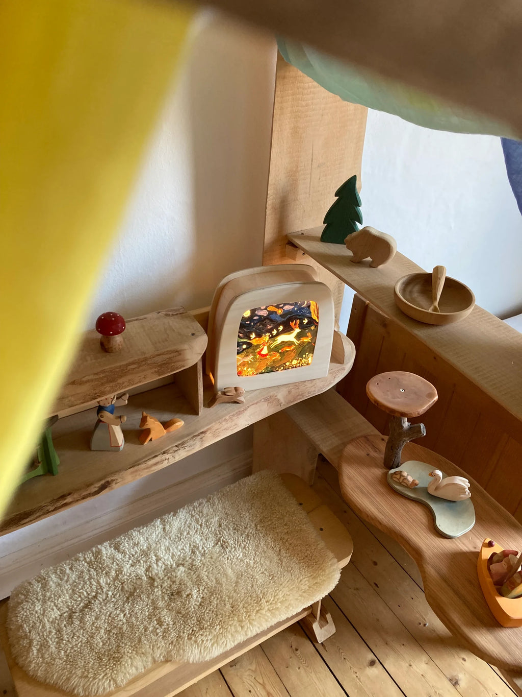 Magische Lampe Toverlux mit leuchtendem Motiv in einer Spielecke mit Schaffell und Holzspielzeug