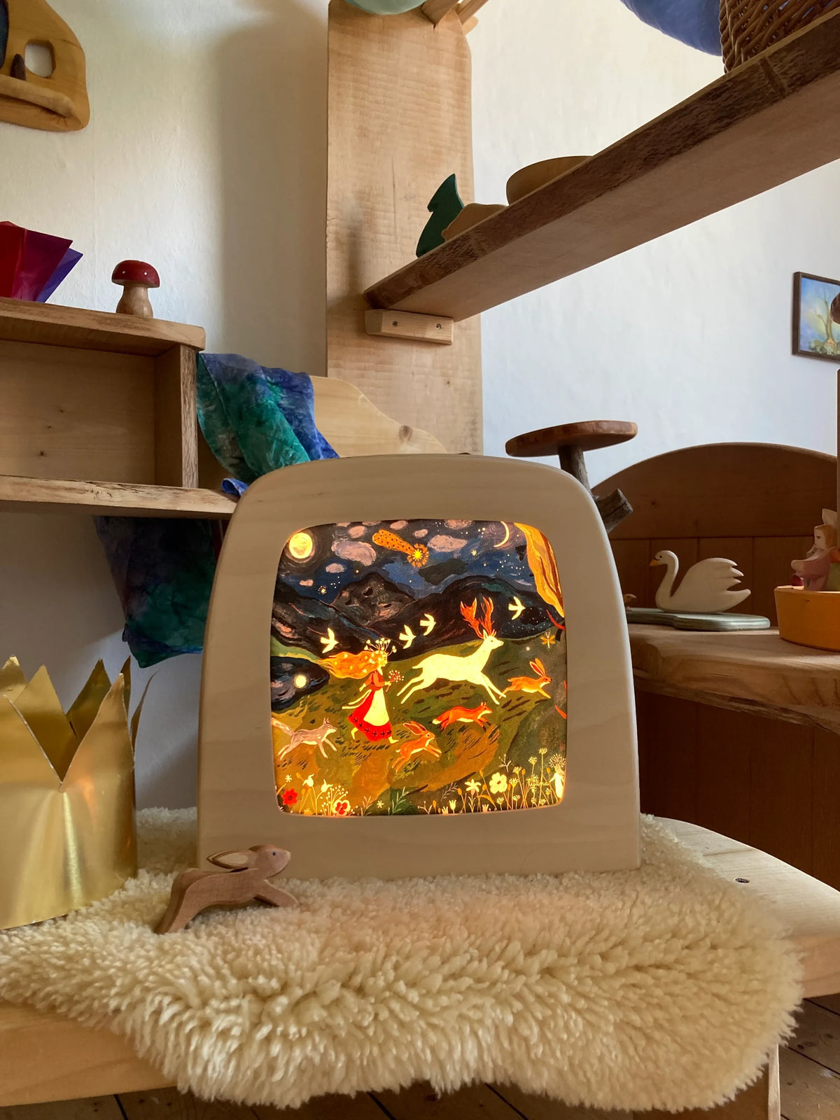 Magische Lampe Toverlux aus Holz mit leuchtendem Nachtmotiv mit springendem Hasen auf einem Schaffell