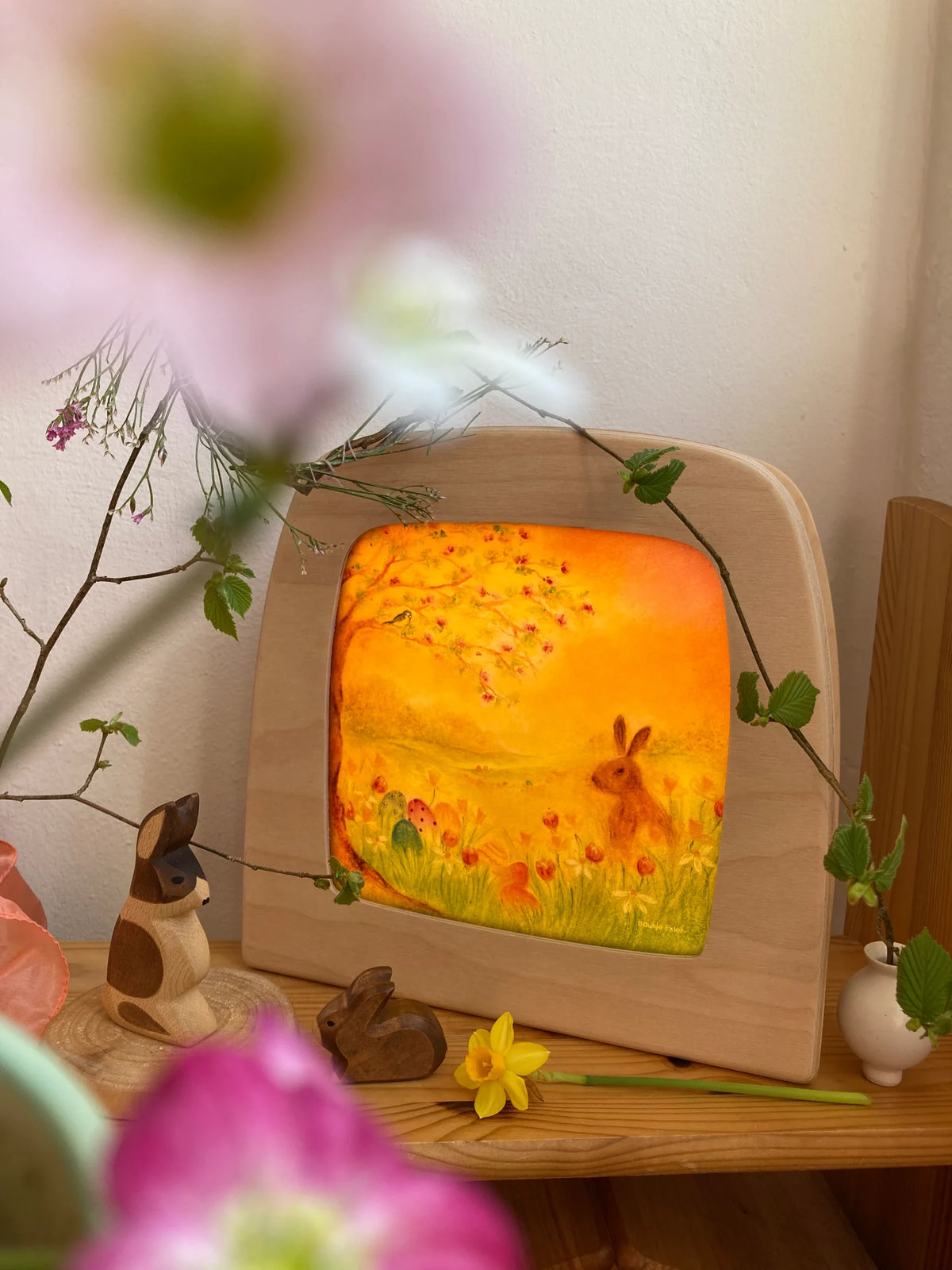 Toverlux Motiv Eiersuche von Baukje Exler: Osterhase leuchtet in der Lampe zwischen rosa Frühlingsblumen und Zweigen
