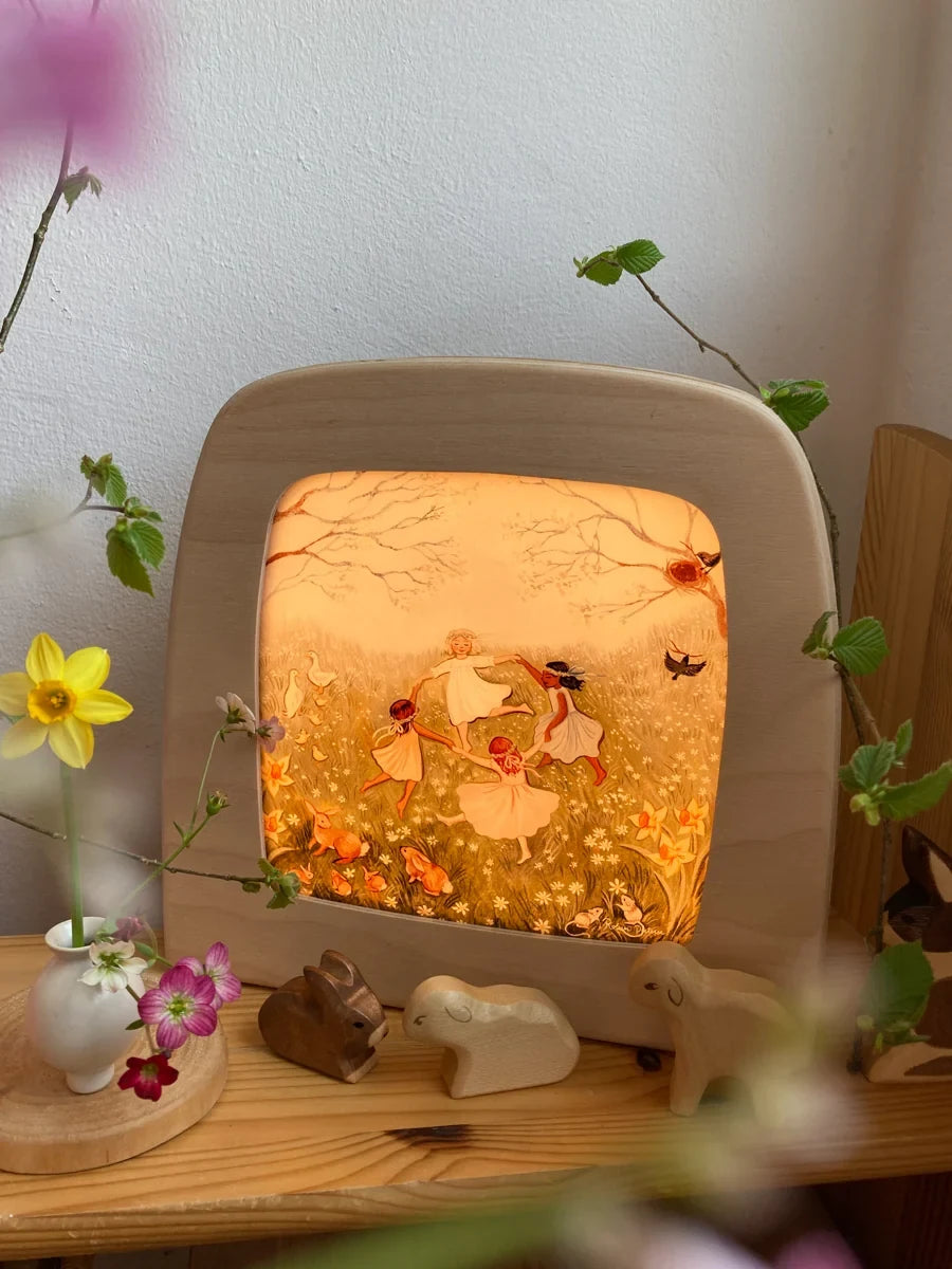 Toverlux Motiv Frühlingstanz von Robin Pieterse: leuchtende Lampe im Regal mit Narzissen, Zweigen und Holztieren