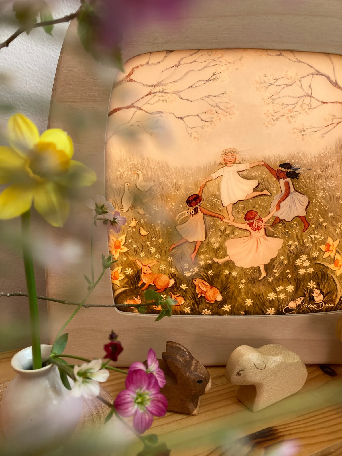 Toverlux Motiv Frühlingstanz von Robin Pieterse: tanzende Kinder in der Lampe aus der Nähe, links eine gelbe Narzisse