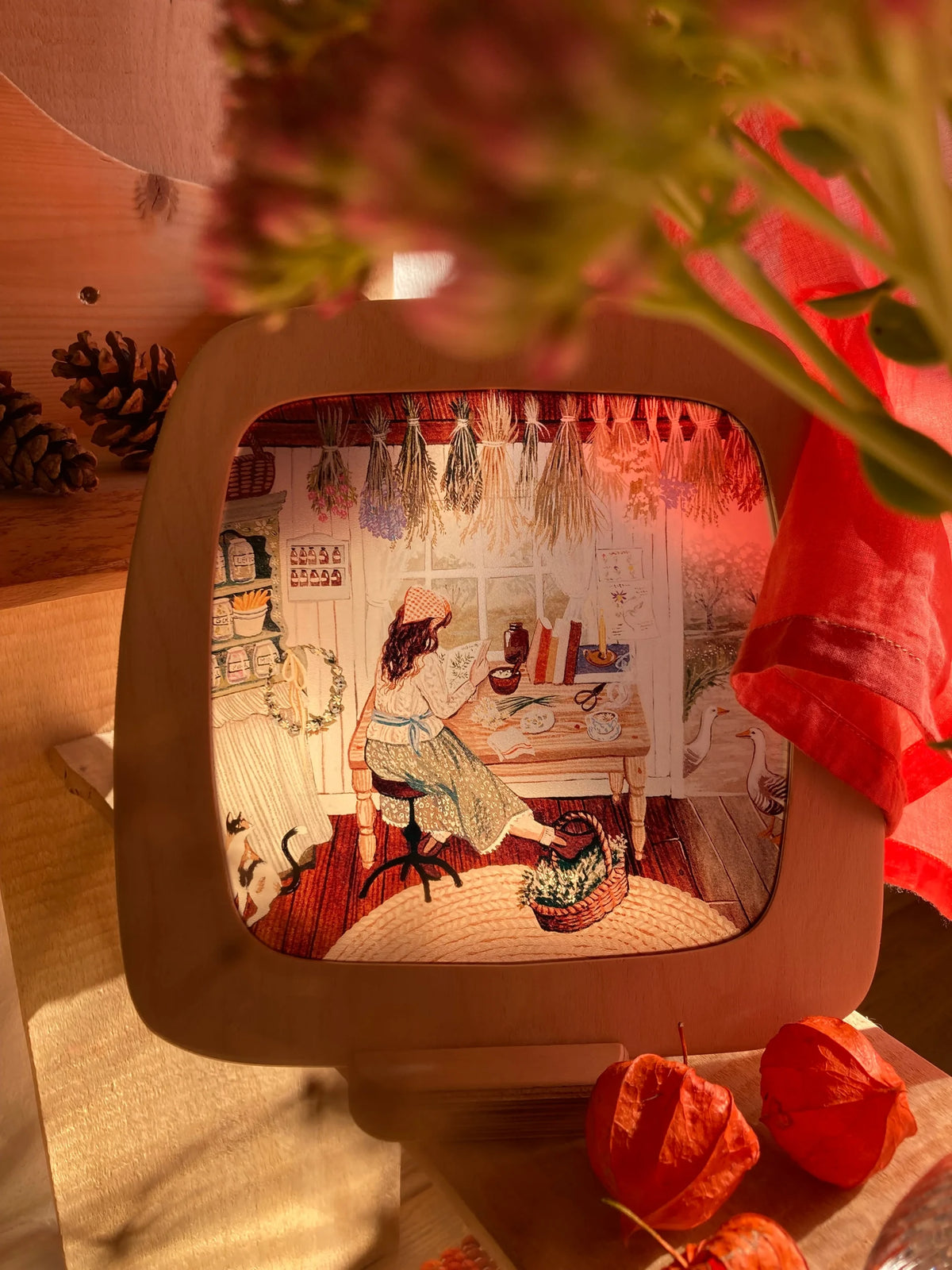 Toverlux Motiv Herbalistin von Robin Pieterse: leuchtende Lampe mit roten Blüten und Lampionblumen davor