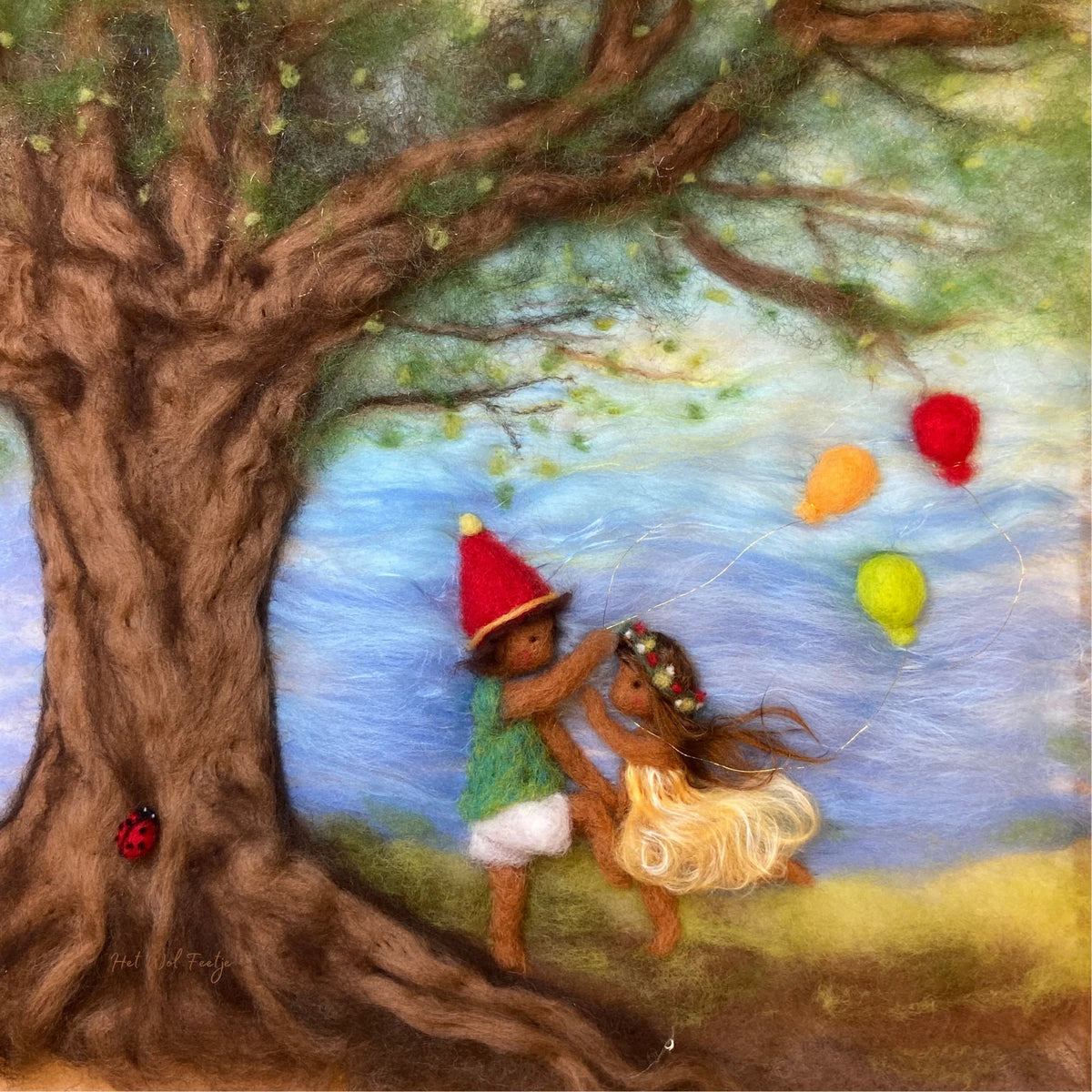 Toverlux Motiv Kinder feiern von Het Wol Feetje, Illustration: Gefilzte Figur mit bunten Luftballons unter einem Baum am See