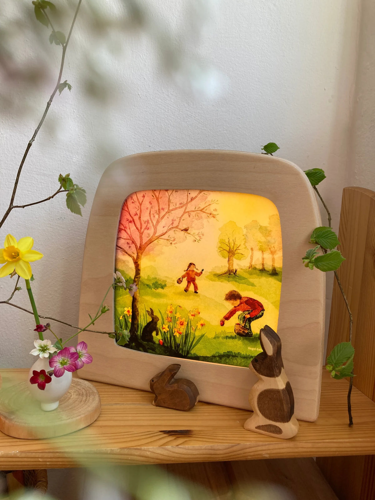 Toverlux Motiv Osterentdeckungen von Vogel Geluk: leuchtende Lampe zwischen Zweigen, Steinen und Frühlingsblumen