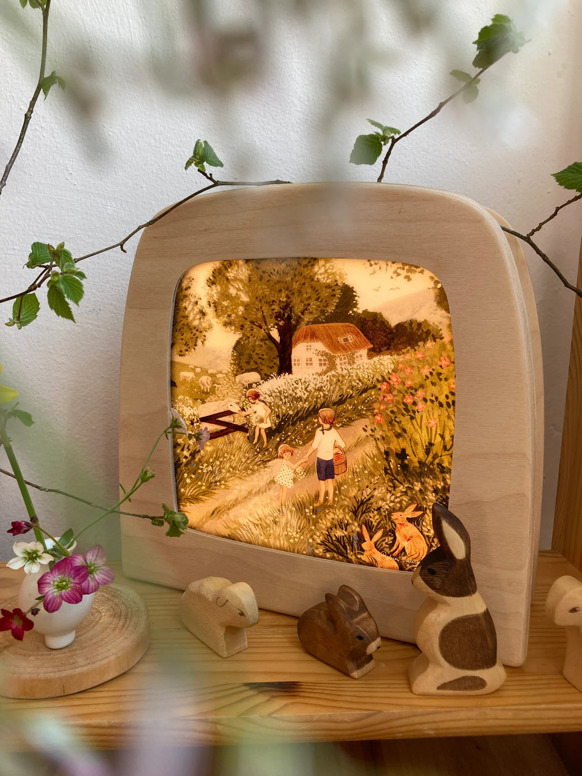 Toverlux Motiv Schafweide von Robin Pieterse leuchtend in der magischen Lampe zwischen Frühlingsblumen
