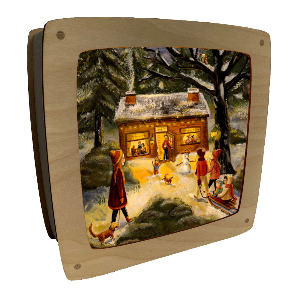 Motiv Winterfest von Esther Bennink für die magische Lampe: Kinder mit Schneemann, Schlitten und Hund vor einem erleuchteten Haus im Schnee